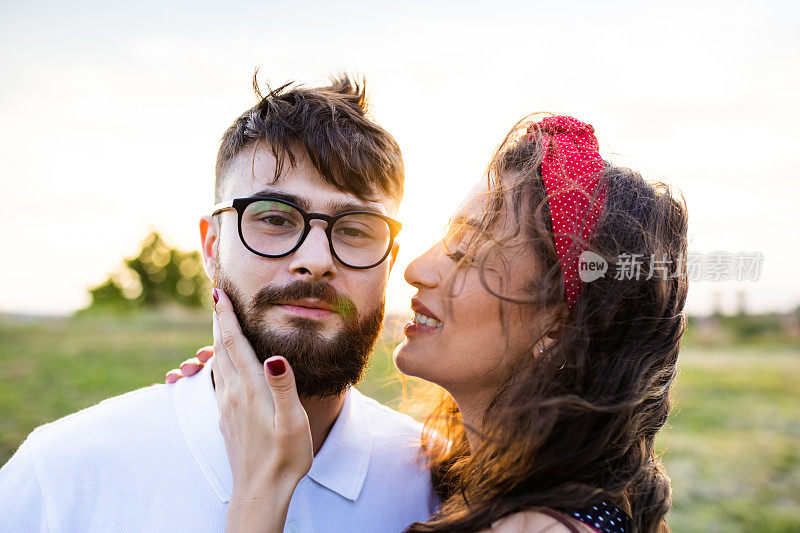 A beautiful young woman about to kiss a young man on the cheek